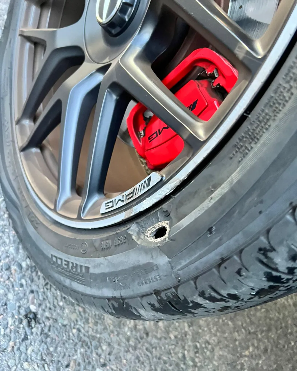Close-up of a nail puncture in the tyre of a Mercedes-AMG with red calipers