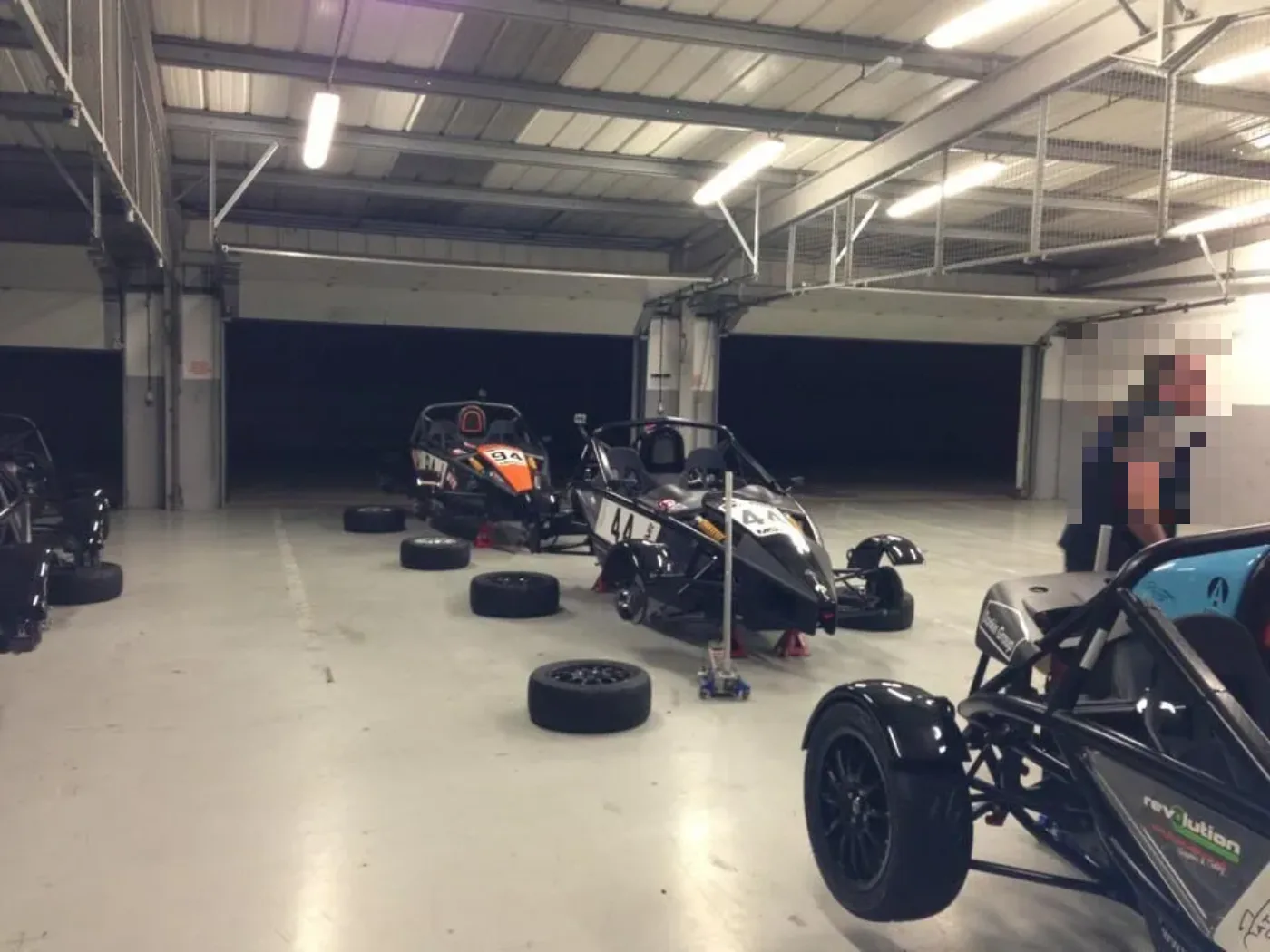 Ariel Atom track cars in a race paddock garage with tyres being changed by Fastrack