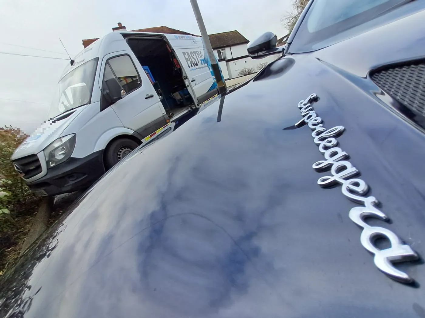 Aston Martin DBS Superleggera bonnet badge beside the Fastrack van