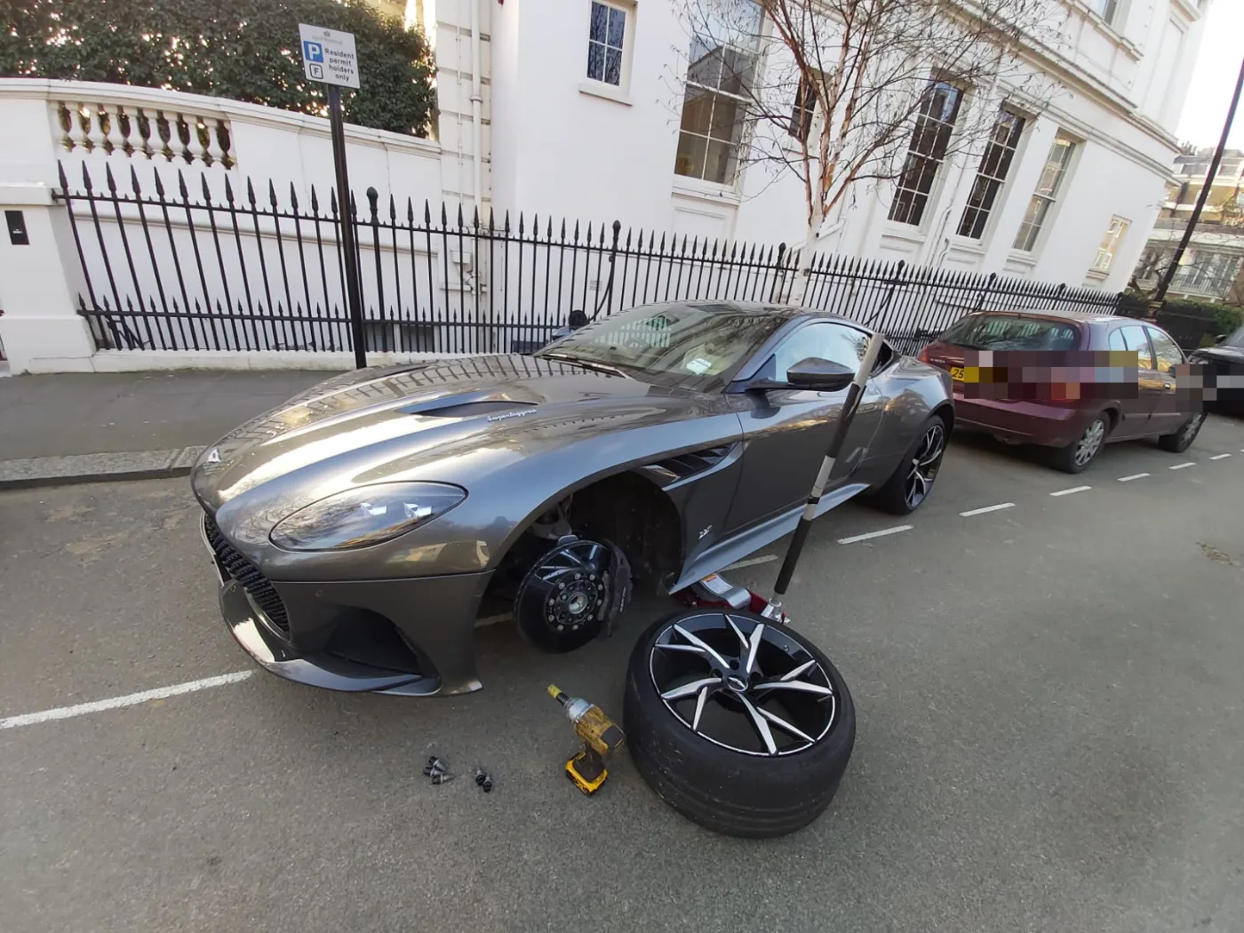 Grey Aston Martin DBS Superleggera kerbside in Notting Hill during a mobile tyre change