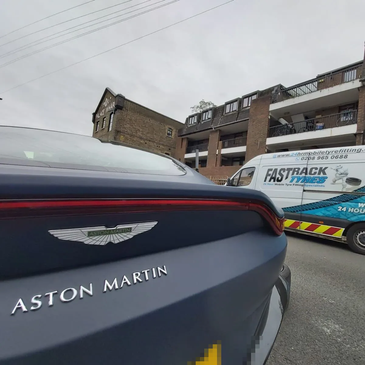 Navy Aston Martin Vantage attended by the Fastrack mobile tyre van near Palace Wharf