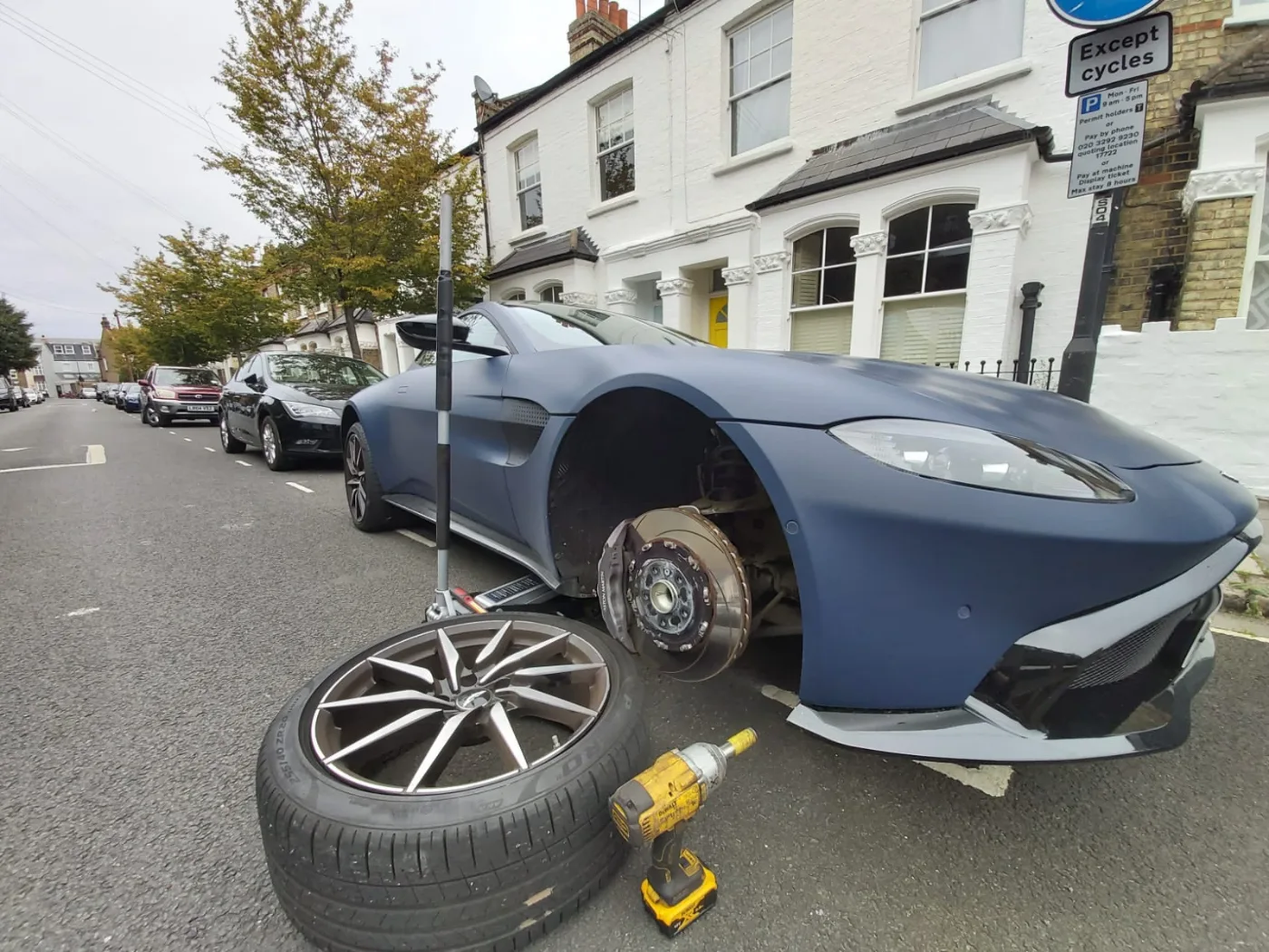 Matte-grey Aston Martin Vantage having a wheel changed on a London street