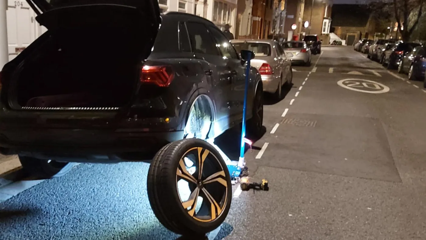 Audi RSQ8 with an illuminated alloy during a night-time mobile tyre change in London