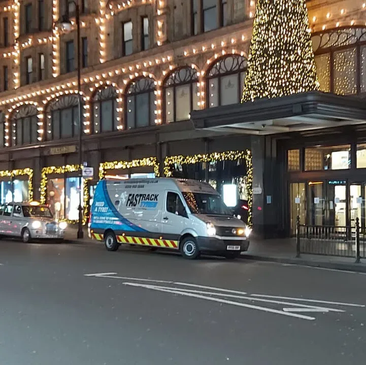 Fastrack mobile tyre van outside Harrods in Knightsbridge lit up with Christmas lights