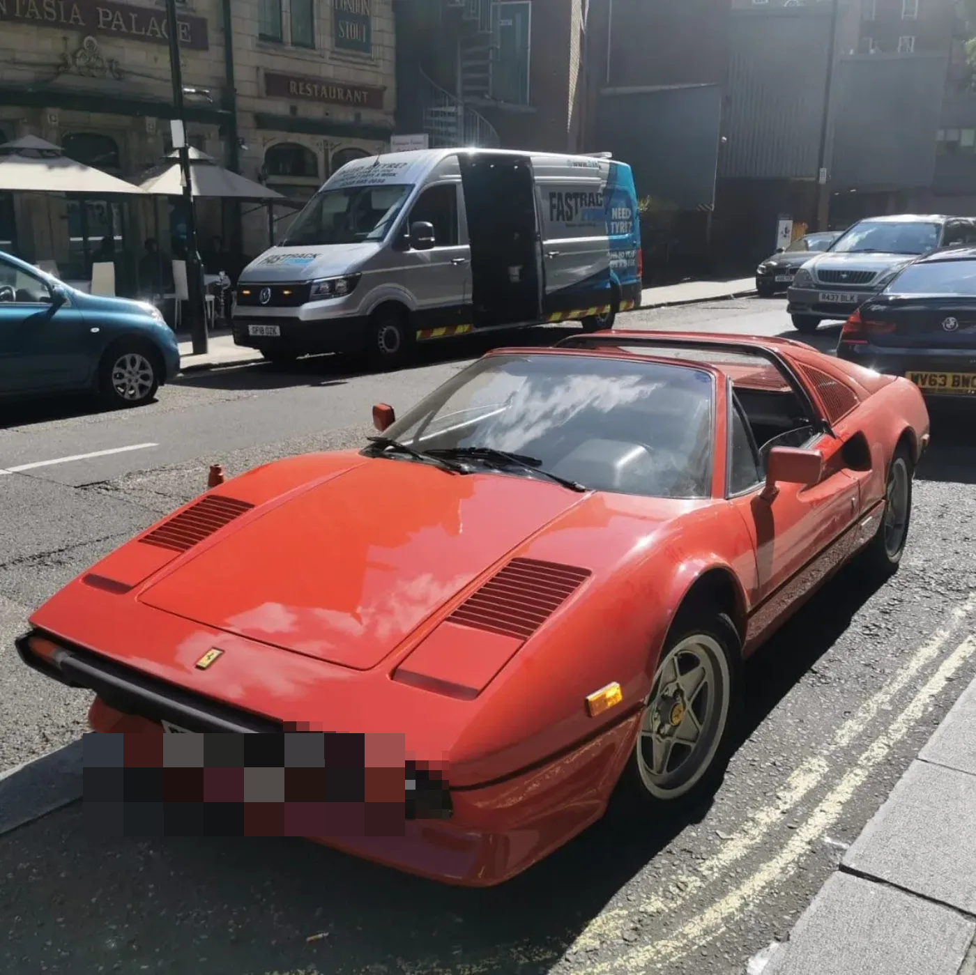 Classic red Ferrari 308 GTB beside the Fastrack van on a foggy London morning