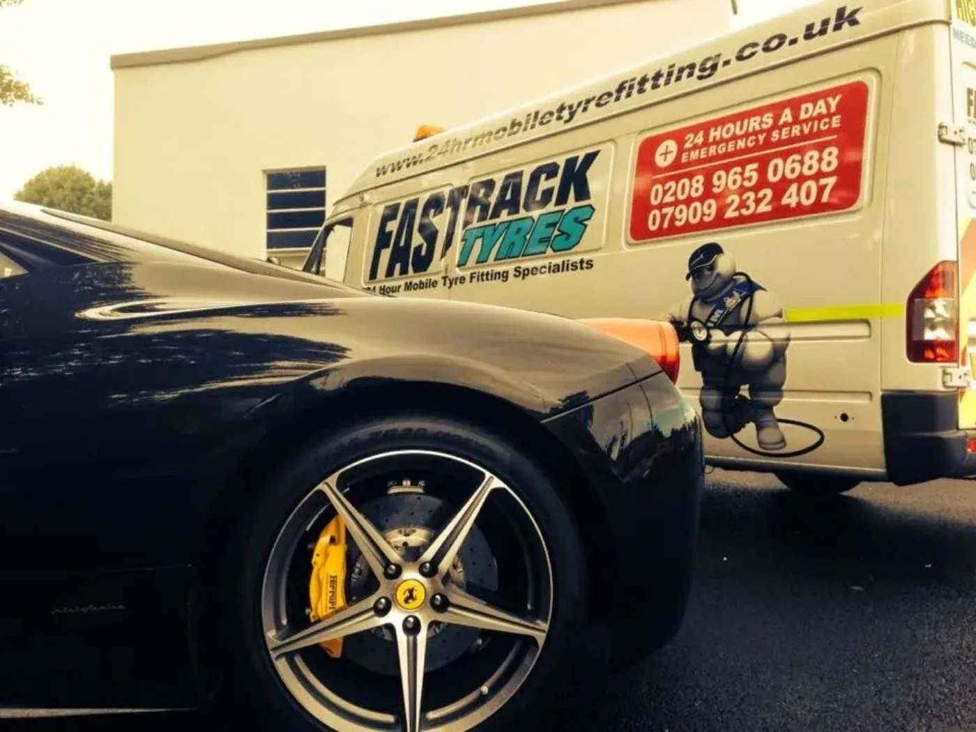 Black Ferrari 458 with yellow calipers beside an early Fastrack van