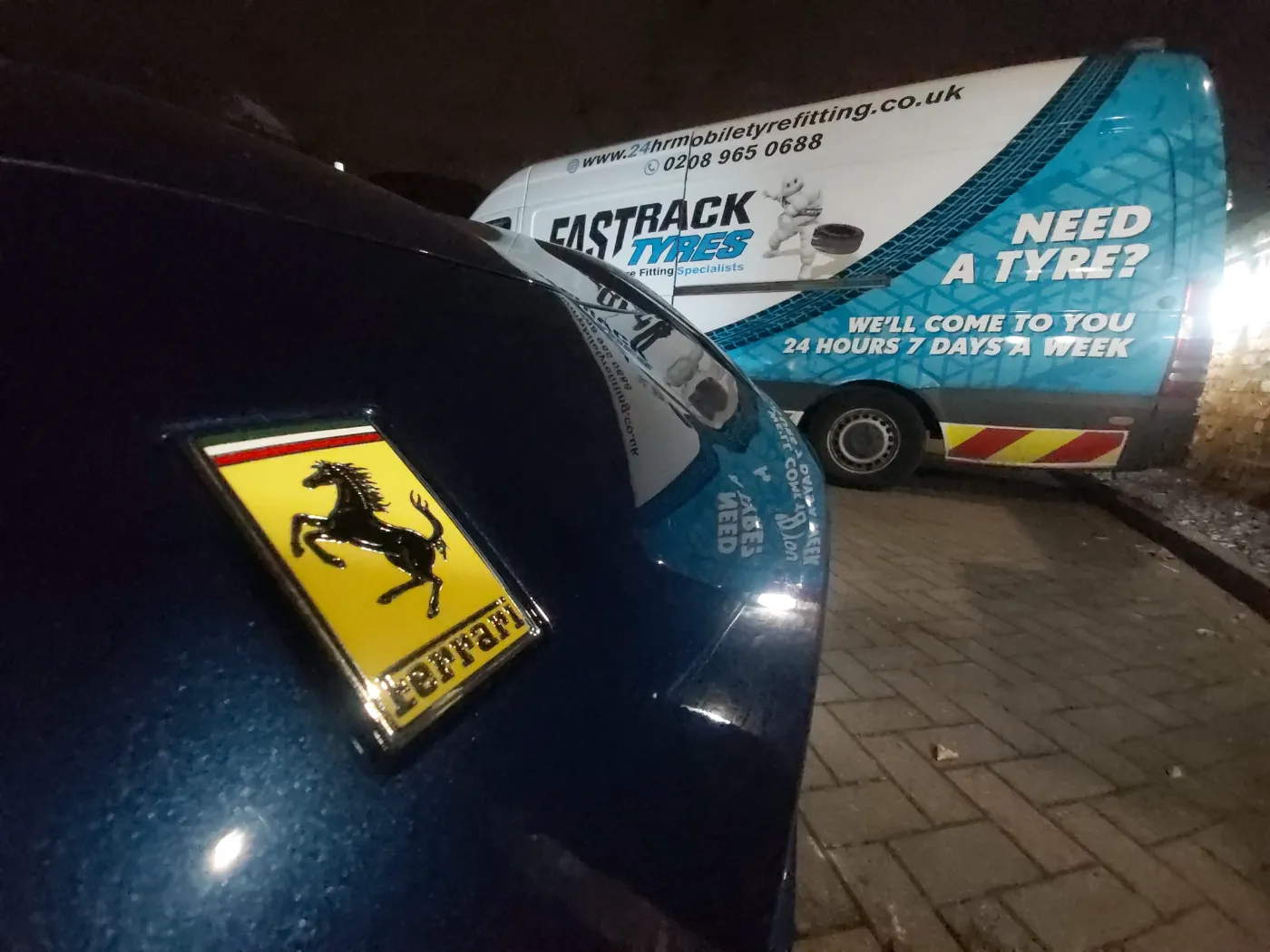 Ferrari bonnet badge at night beside the Fastrack mobile tyre van