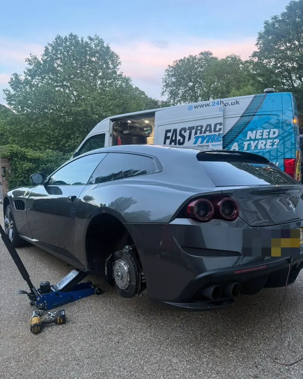 Ferrari GTC4Lusso with the rear wheel removed during a mobile tyre fitting at dusk