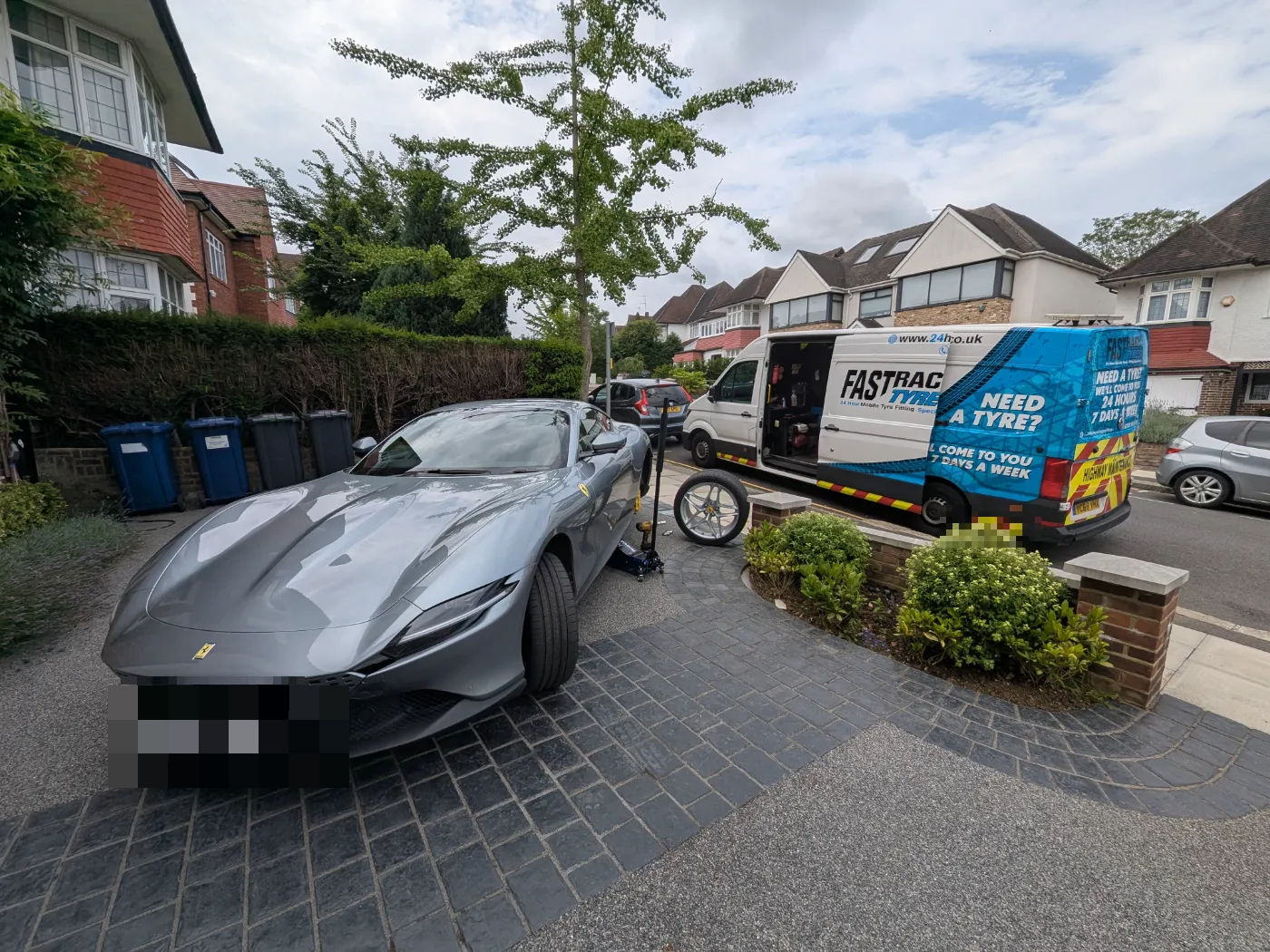 Grey Ferrari Roma having a wheel changed at the kerbside
