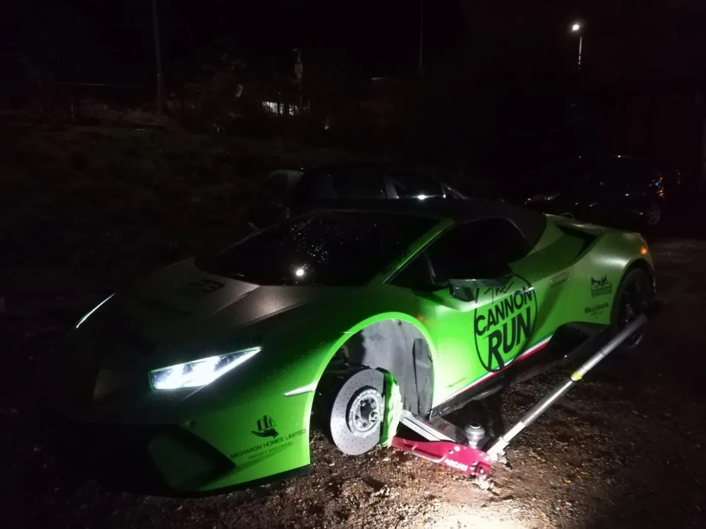 Green Cannon Run Lamborghini Huracan having a wheel changed at night