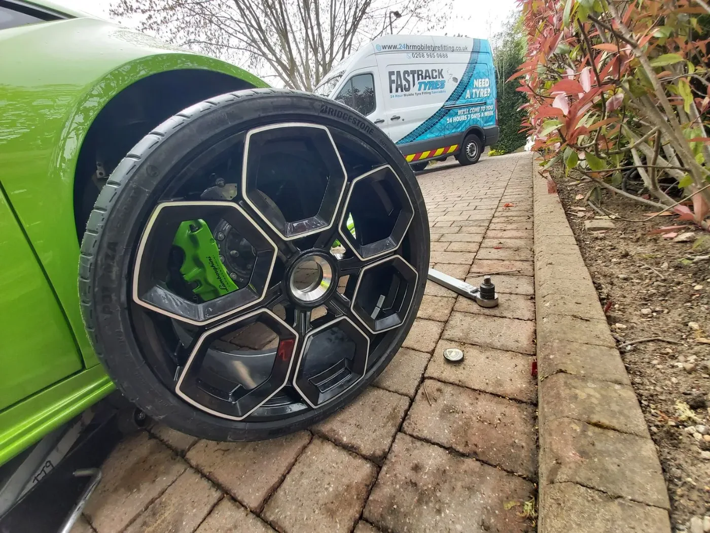 Green Lamborghini Huracan with a wheel removed during a mobile tyre change
