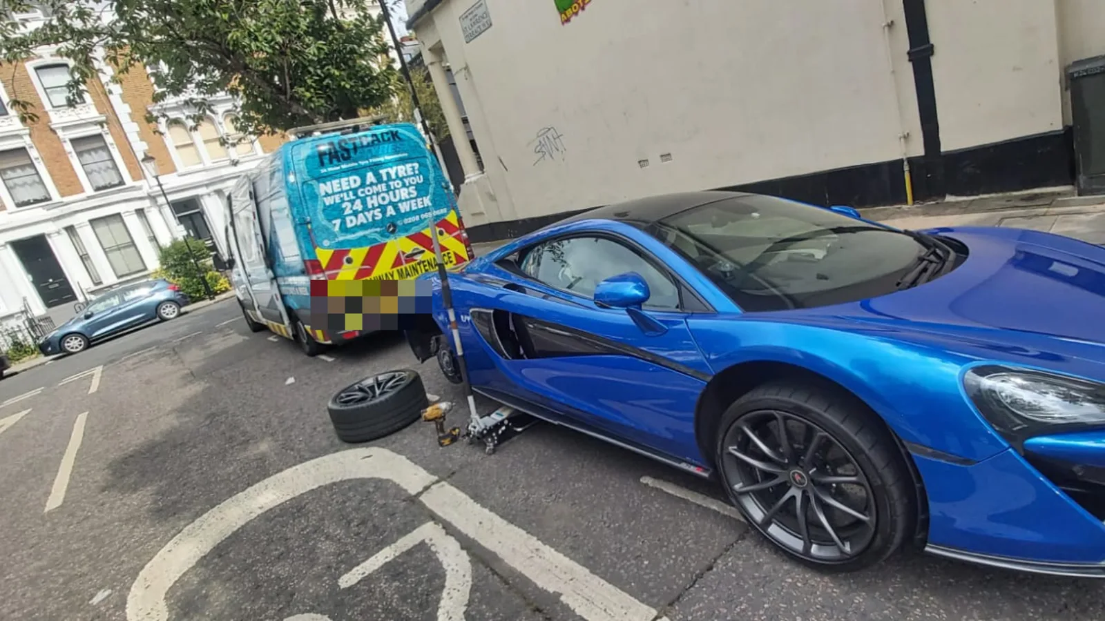 Blue McLaren 570S beside the Fastrack van during a roadside mobile tyre change in London