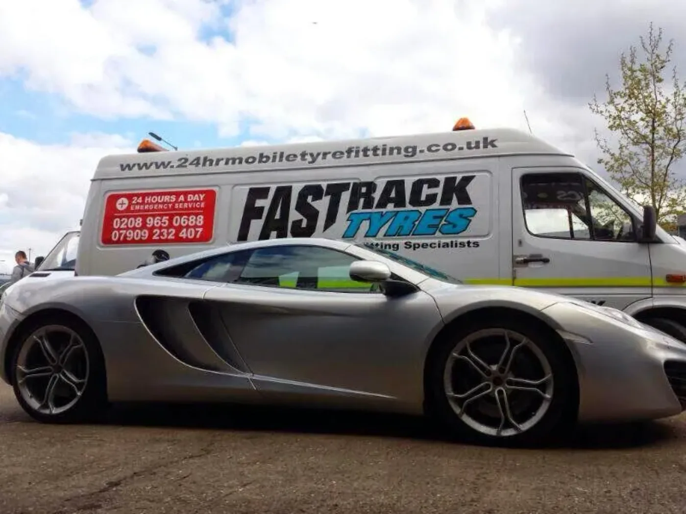 Silver McLaren MP4-12C beside the Fastrack van on a London street