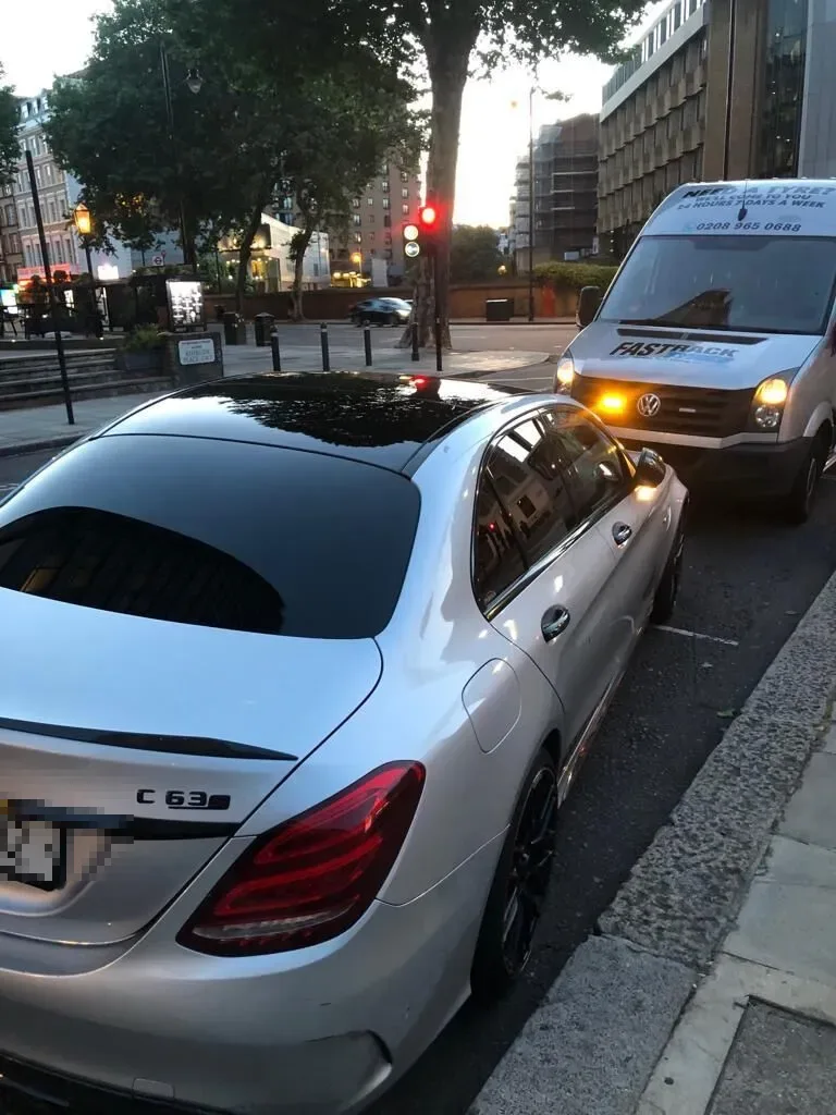 Silver Mercedes-AMG C63 S saloon with the Fastrack Tyres van behind at dusk during a roadside tyre change