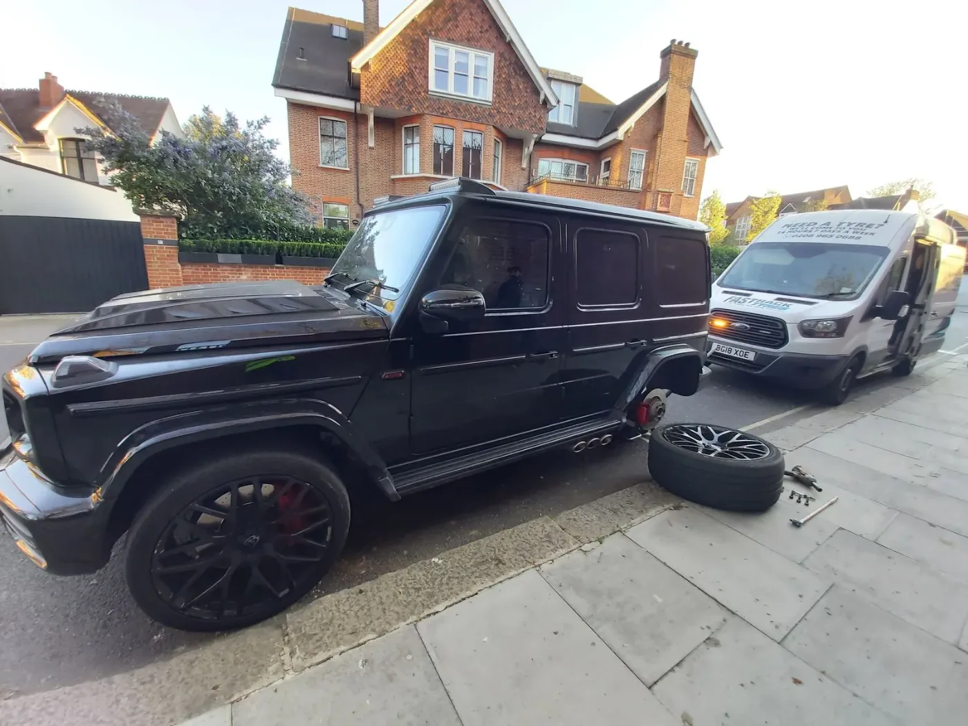Black Mercedes-AMG G63 with a wheel off during a mobile tyre change