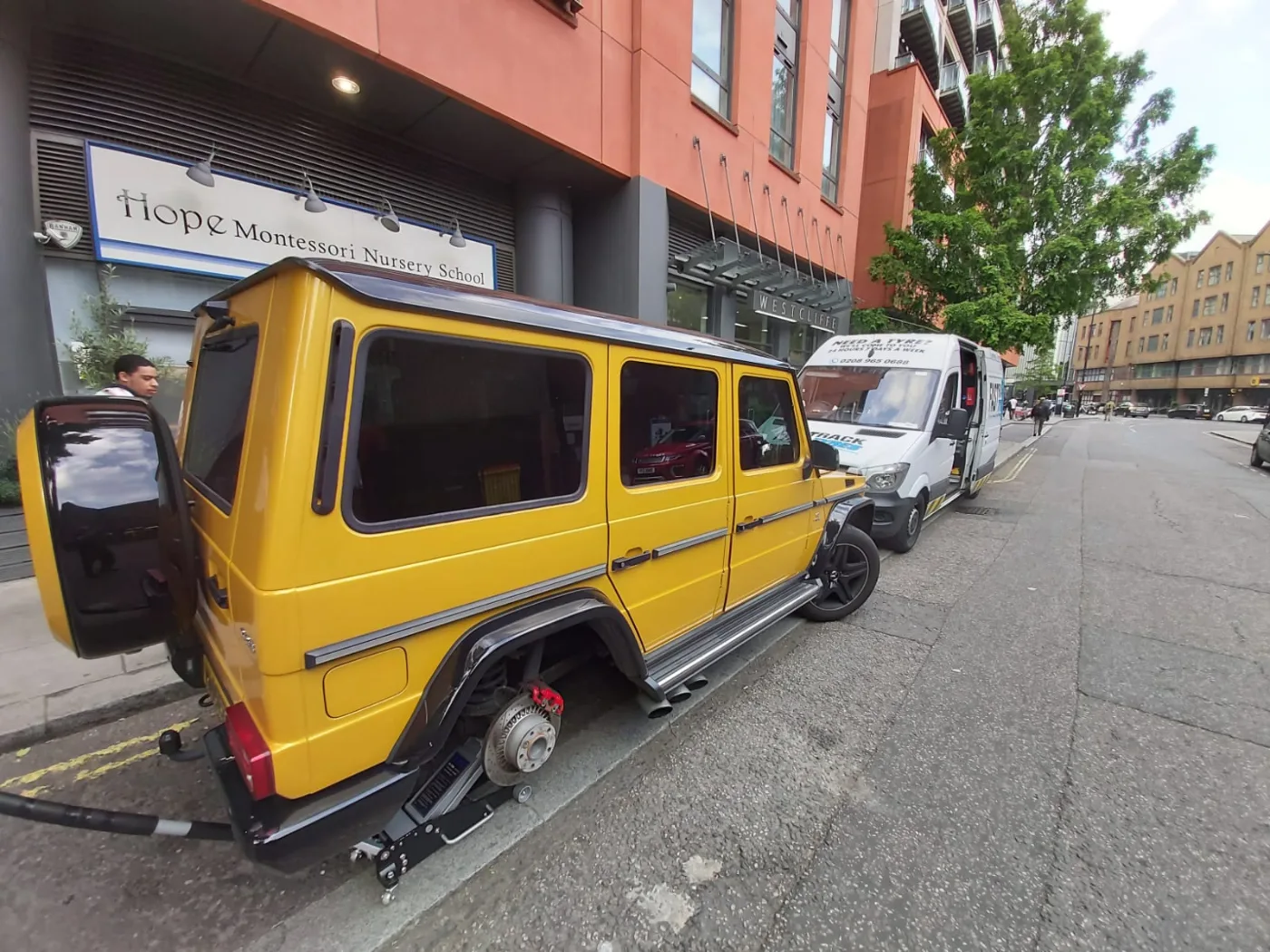 Yellow Mercedes G-Wagon having a tyre changed kerbside by Fastrack