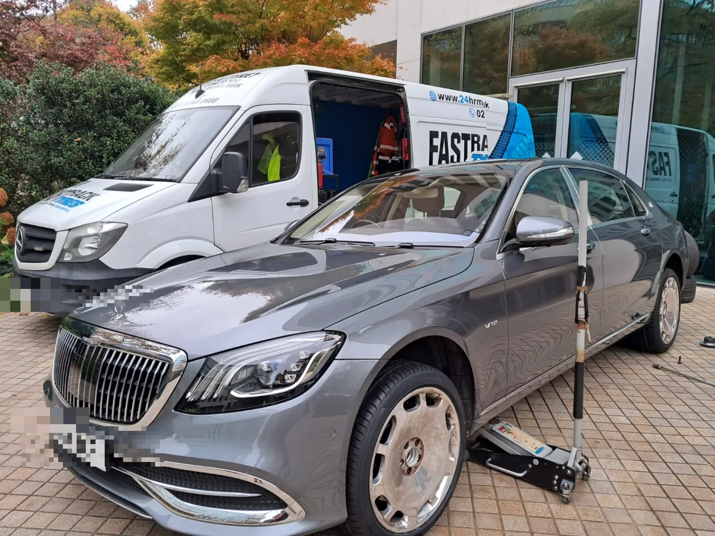 Mercedes-Maybach S-Class having a wheel changed beside the Fastrack van