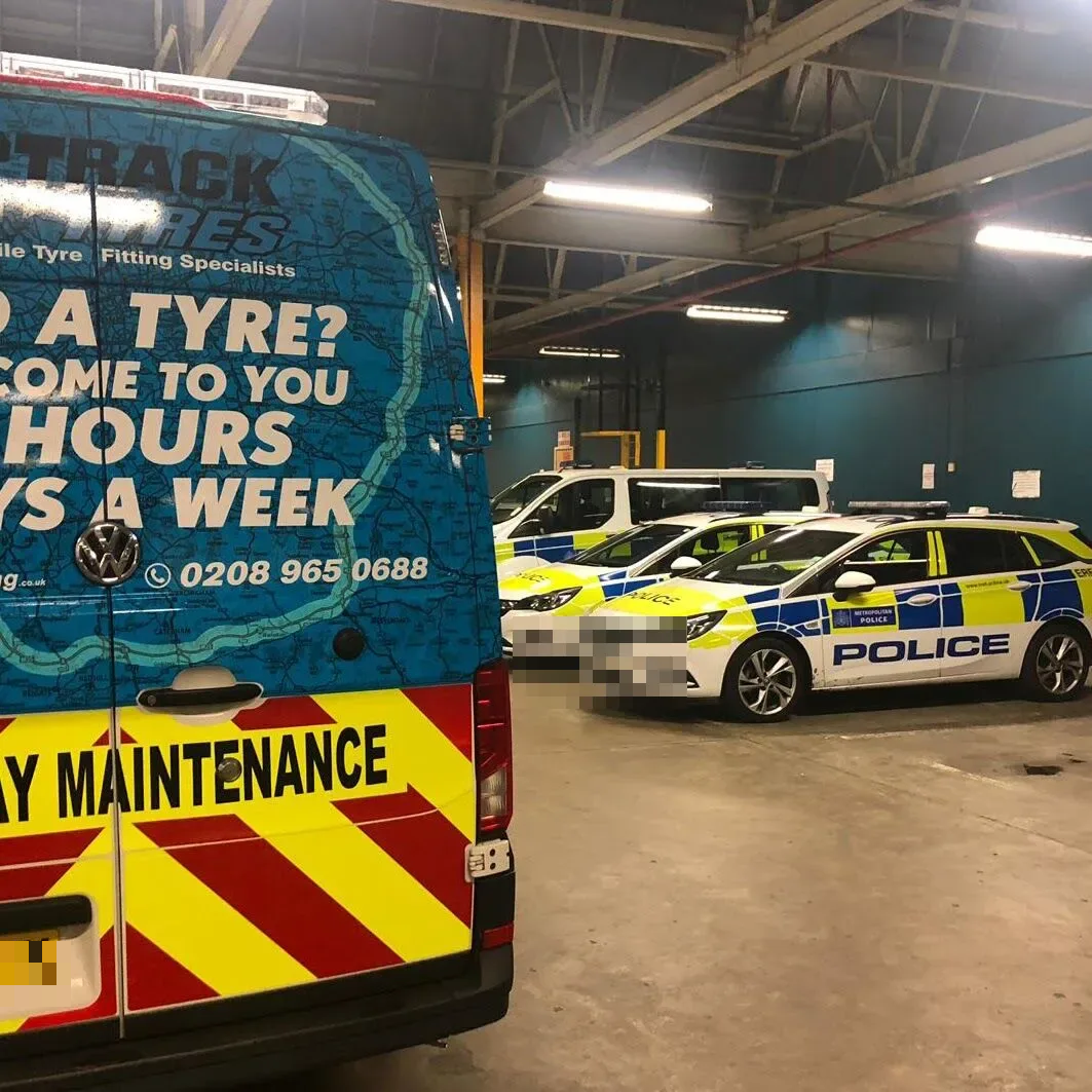 Fastrack van alongside Metropolitan Police patrol cars at a fleet depot