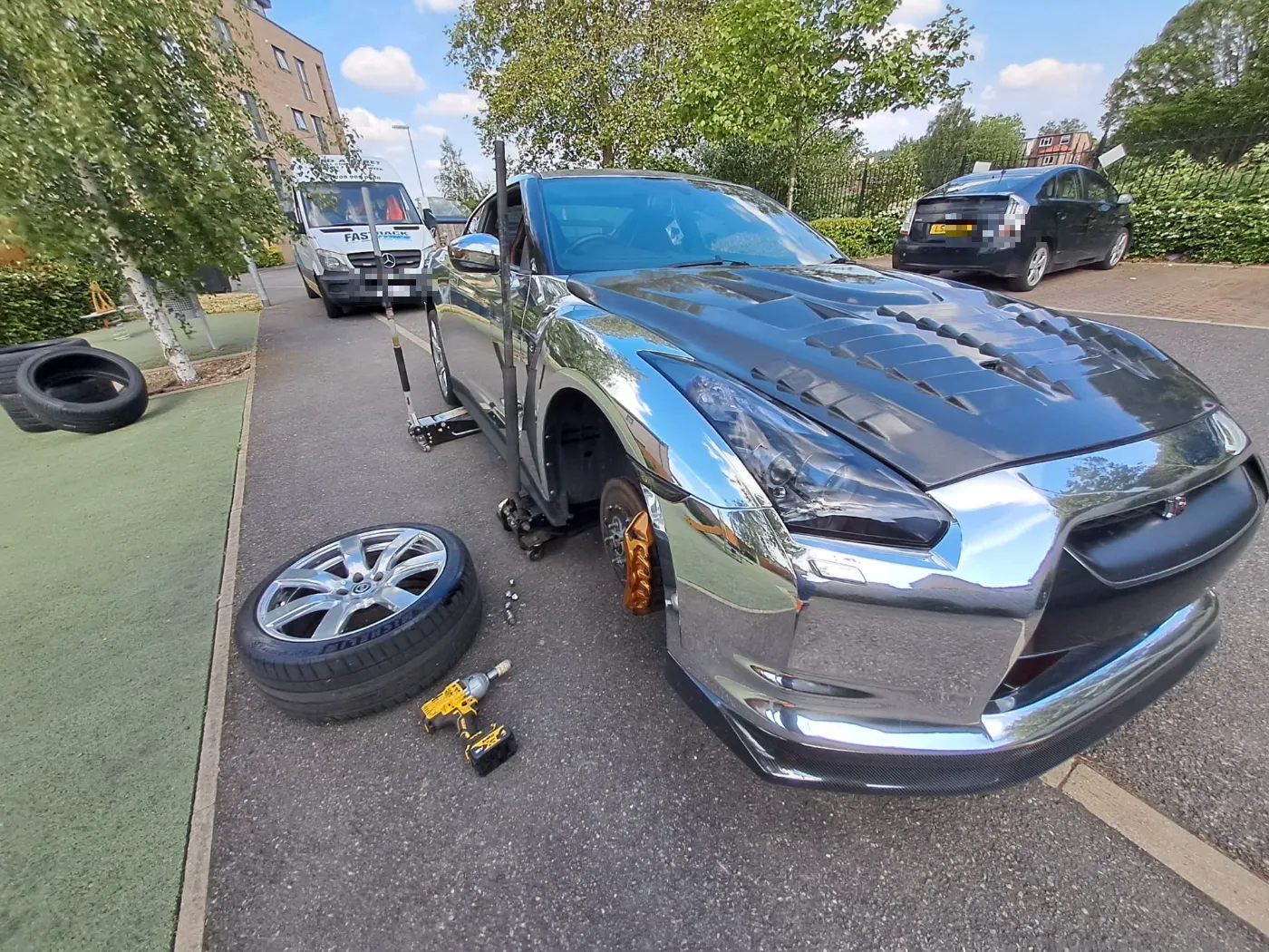 Chrome-wrapped Nissan GT-R with a wheel off for a mobile tyre replacement