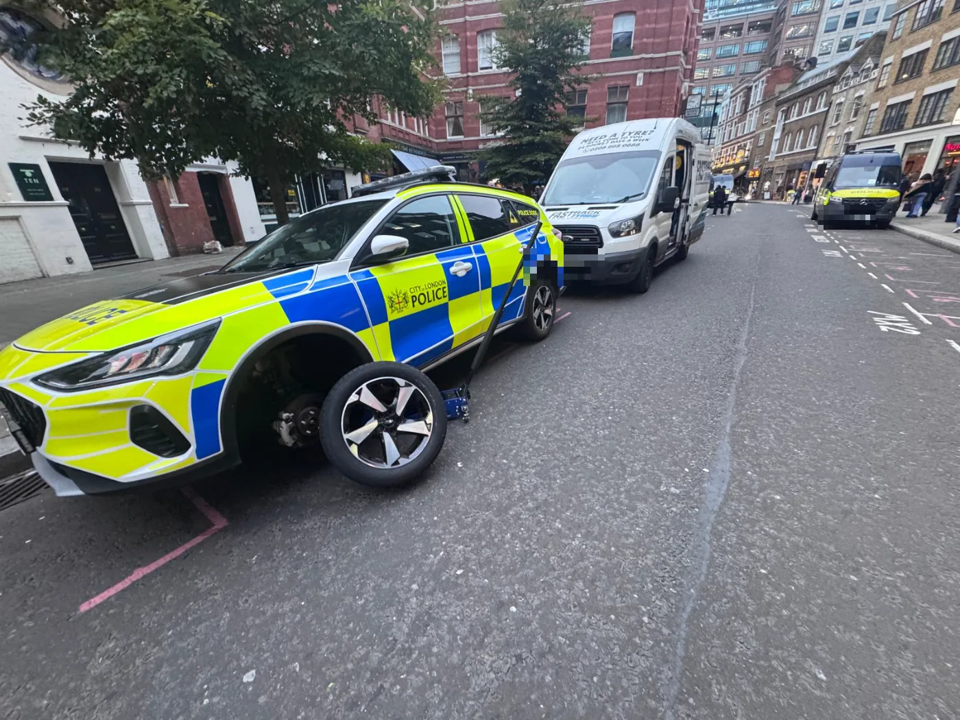 Fastrack changing a wheel on a City of London Police car on a London street