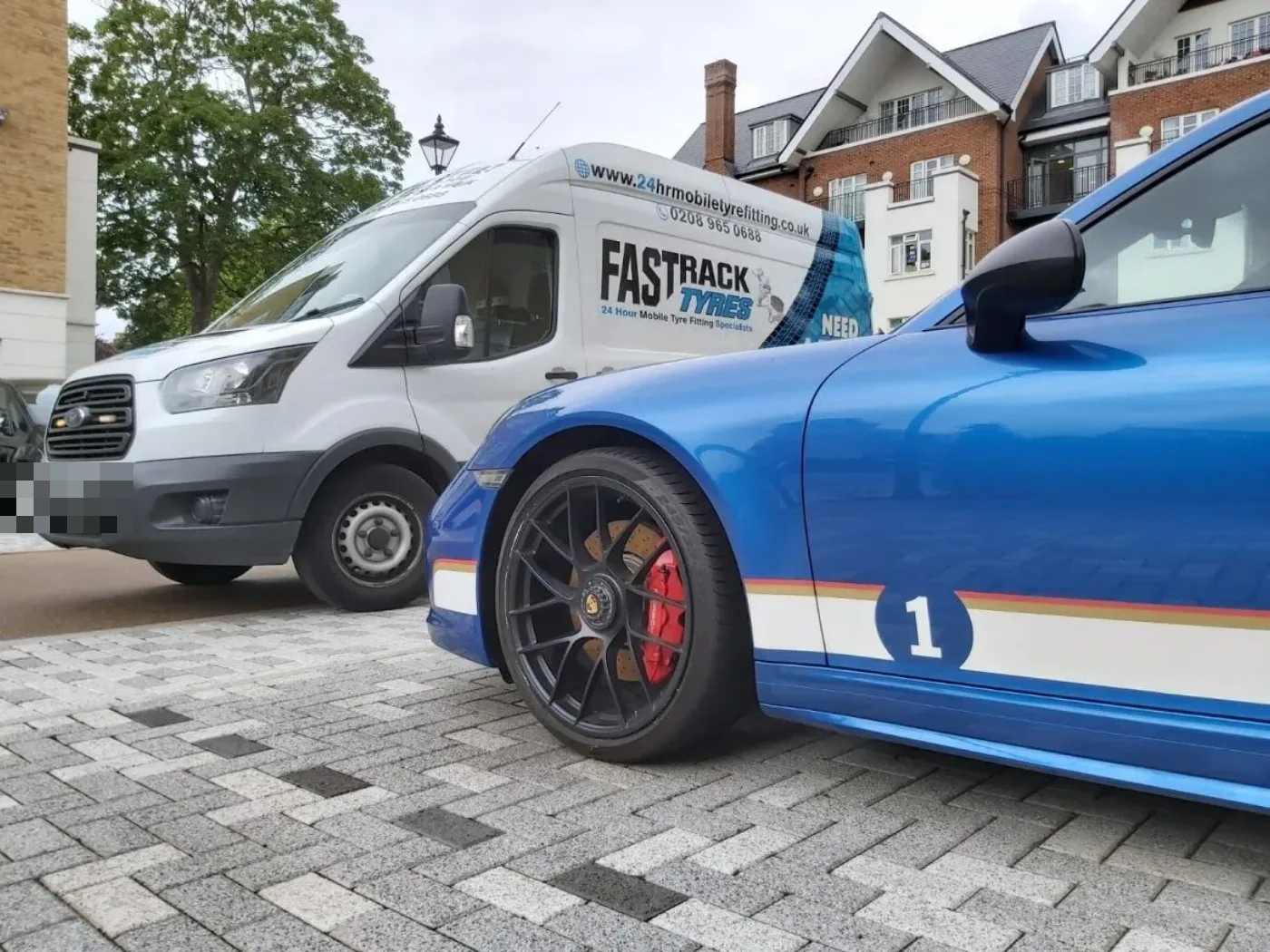 Blue Porsche 911 in racing livery on a driveway during a mobile tyre fit