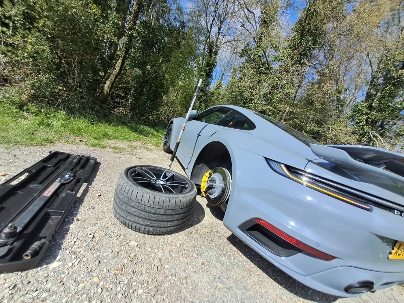 Porsche 911 Turbo S on a country lane having a wheel changed