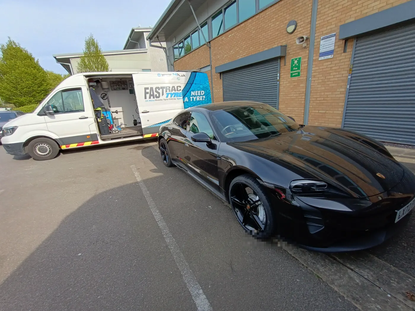 Black Porsche Taycan beside the Fastrack mobile tyre van at a business unit