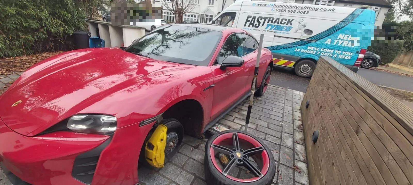 Red Porsche Taycan on a driveway with a wheel removed showing yellow brake calipers and the alloy laid on the ground