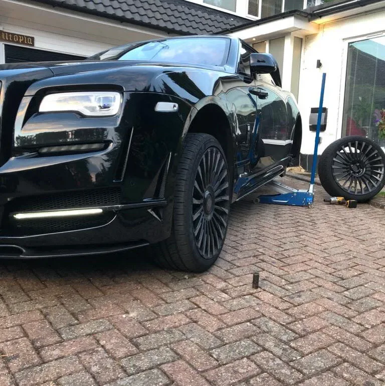 Black Rolls-Royce Dawn raised on a jack for a wheel-off tyre change on a driveway