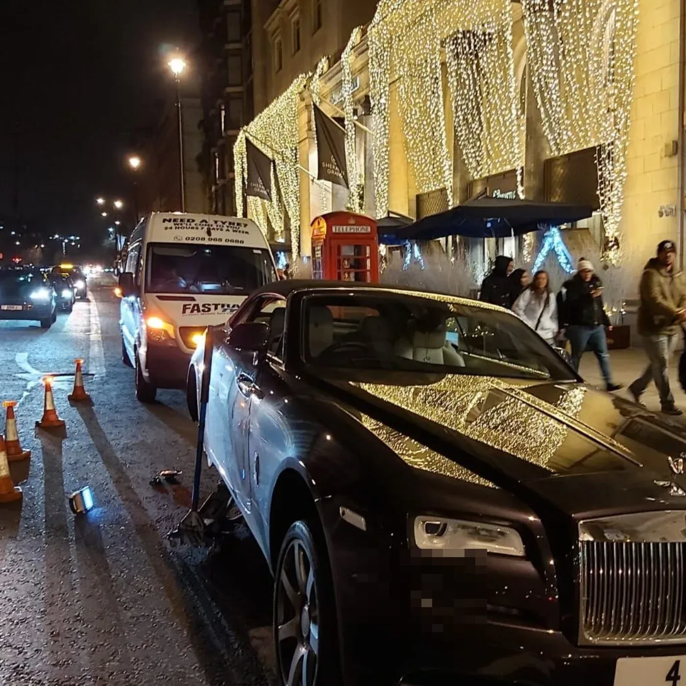 Rolls-Royce Wraith having a wheel changed on a festive Mayfair street