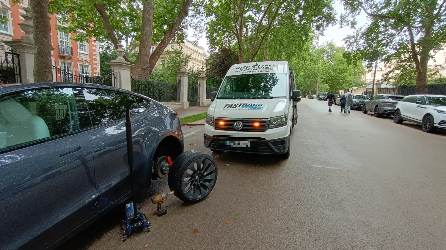 Tesla with a wheel off for a mobile tyre change on a Mayfair street
