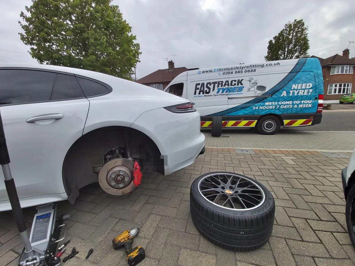 White Porsche Panamera having a tyre replaced at the kerbside by Fastrack